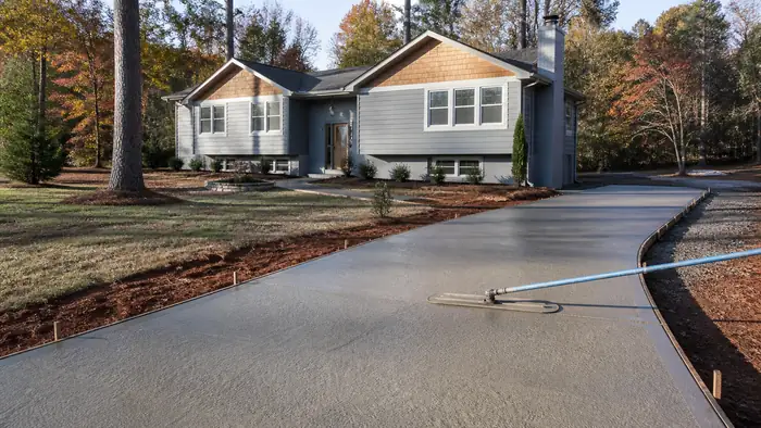 A bull float smooths a residential walkway surface after screeding. at a grey split-level home in Lawrenceville, GA, under low winter sun.