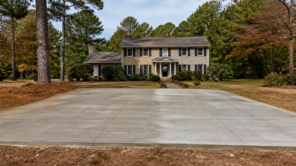 general concrete construction completed by a local contractor at a tan-brick colonial in Lawrenceville, GA, under bright midday cloud.